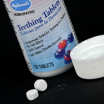Bottle of Hyland's teething tablets with lid off and two tablets out on the table