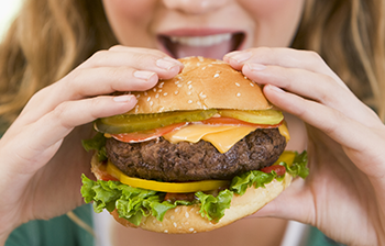 happy teenage girl eating big cheeseburger (350x224)