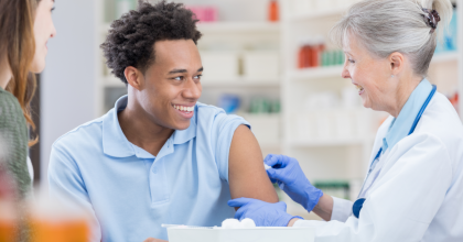 Black male getting flu shot at pharmacy.