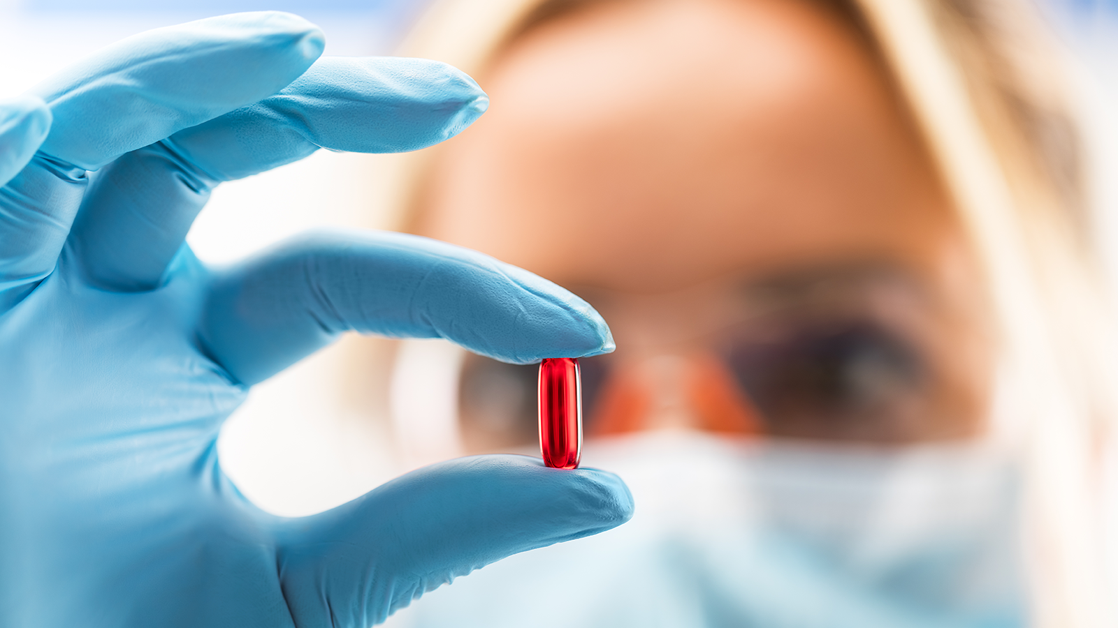 Female scientist holding a red capsule pill