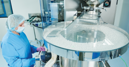 Woman sorting pills at drug manufacturing plant. 