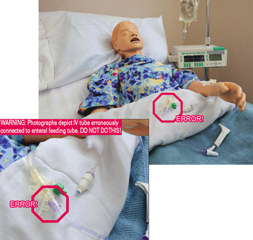 IV tubing erroneously connected to enteral feeding tube on a mannequin in hospital bed.