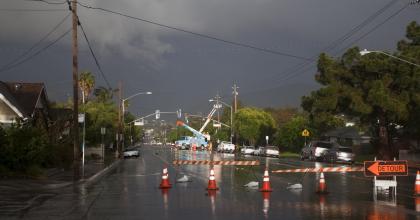 Flooded residential neighborhood with emergency equipment to repair power outage.