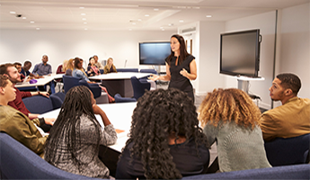 Woman in classroom teaching students. Getty Images