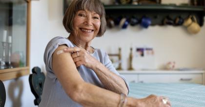 Lady pointing to bandaid on upper arm.