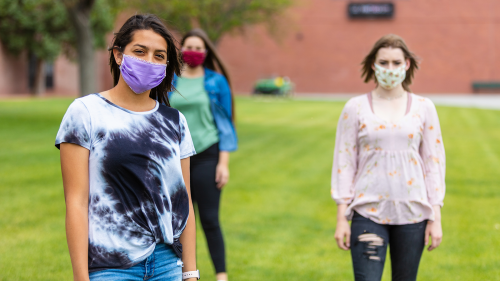 three teen girls wearing face masks on school grounds