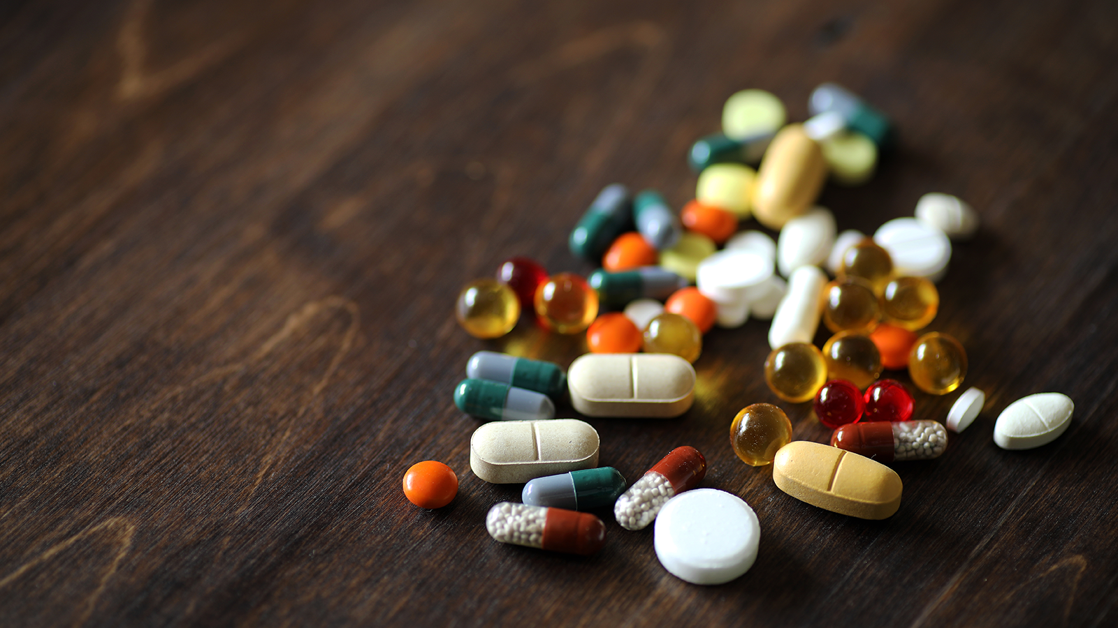 A pile of mixed pills on a wood table