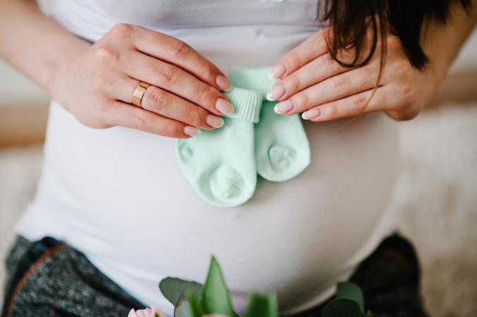 Pregnant woman with baby socks on belly