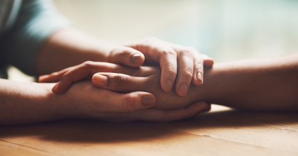 Close-up photo person holding the hand of another person, showing of support.