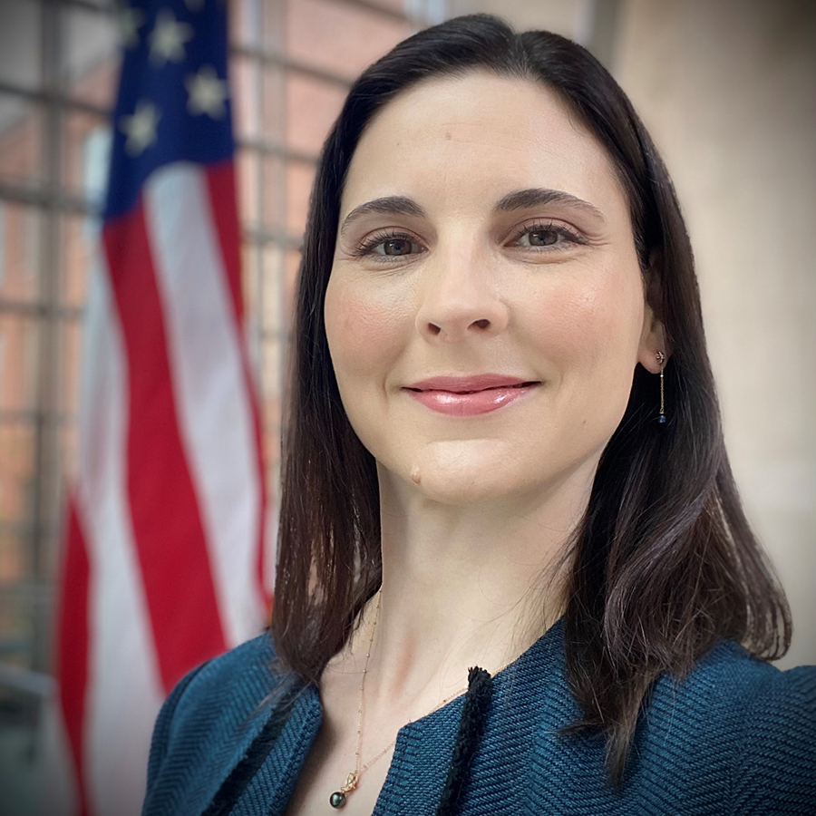 Portrait of Tina Morrison smiling at the camera with soft focus U.S. flag in the background