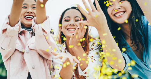 happy women tossing yellow confetti