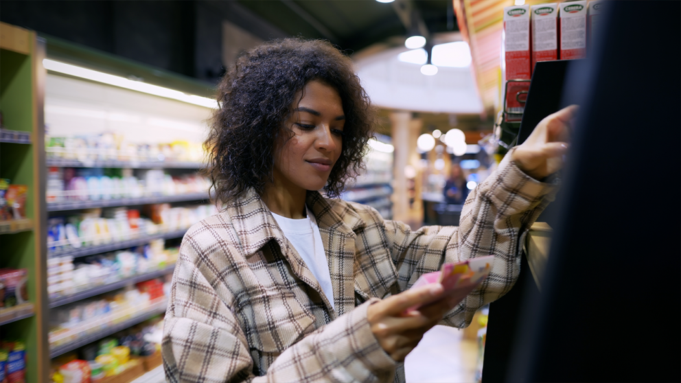 Photo of woman reading label on product in store aisle.