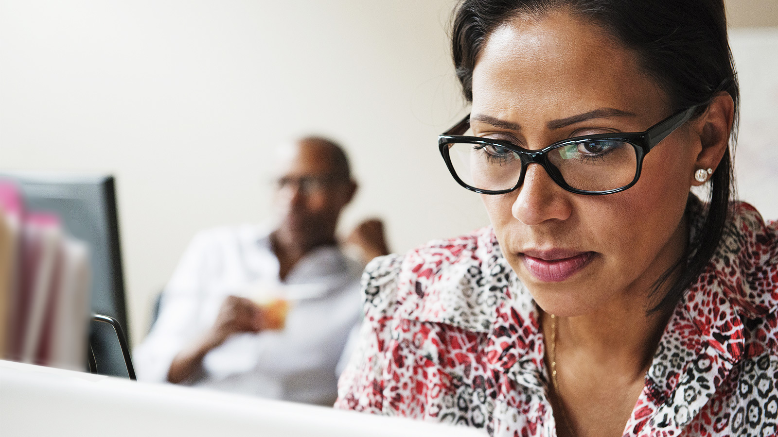 Woman looking at computer with man in the background