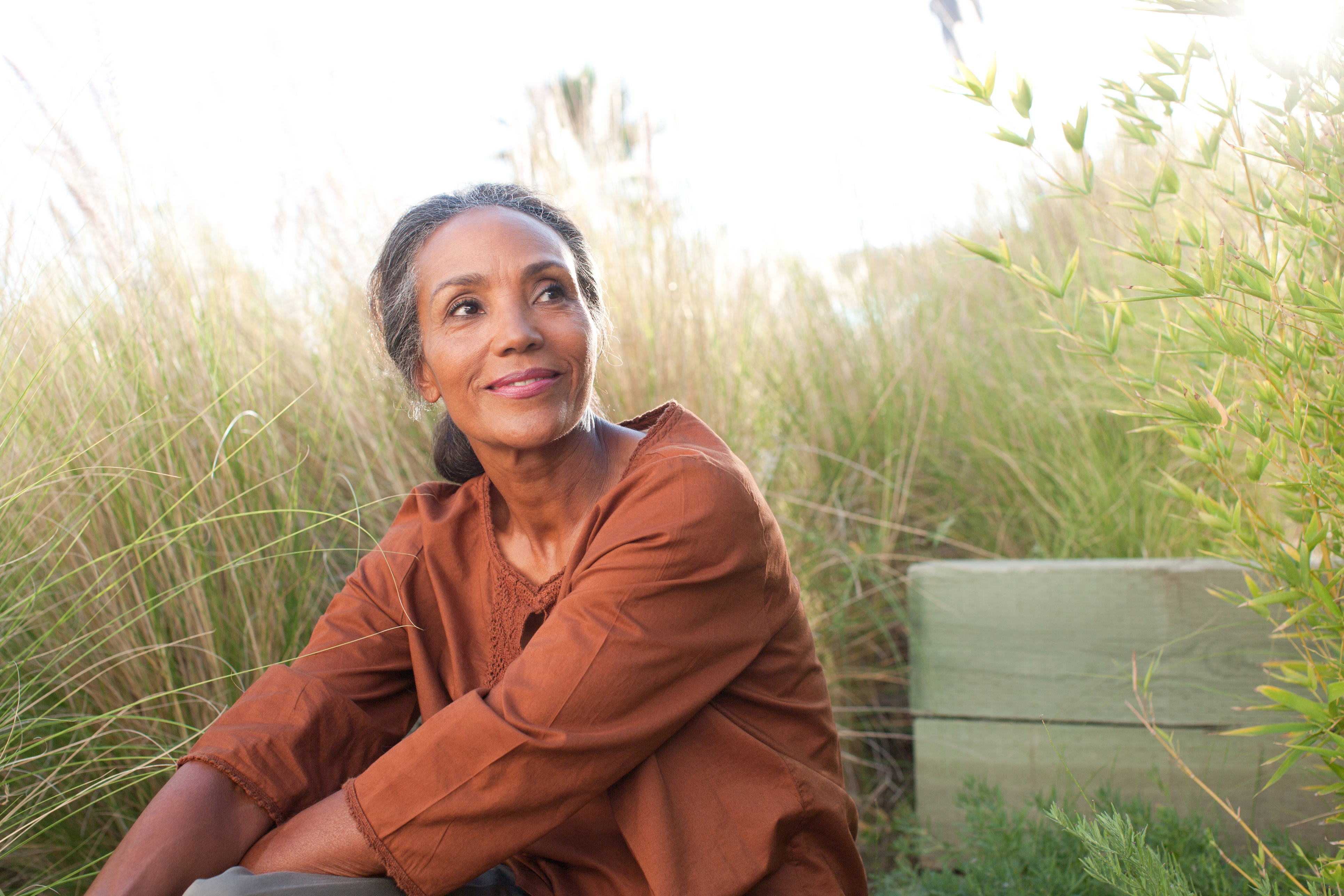 Serene woman sitting in sunny field stock photo