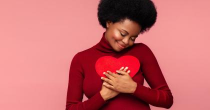 Young woman hugging a paper stock heart