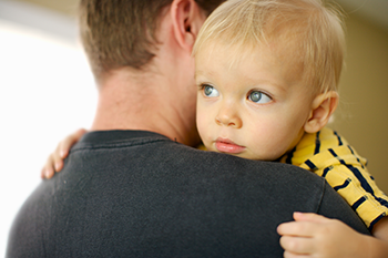 little boy resting head on dad's shoulder