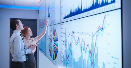 People collaborating near a white board with multiple charts