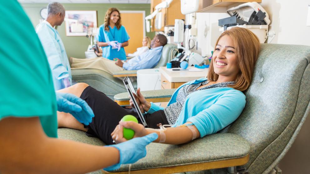 Smiling young asian woman donating blood in clinic.