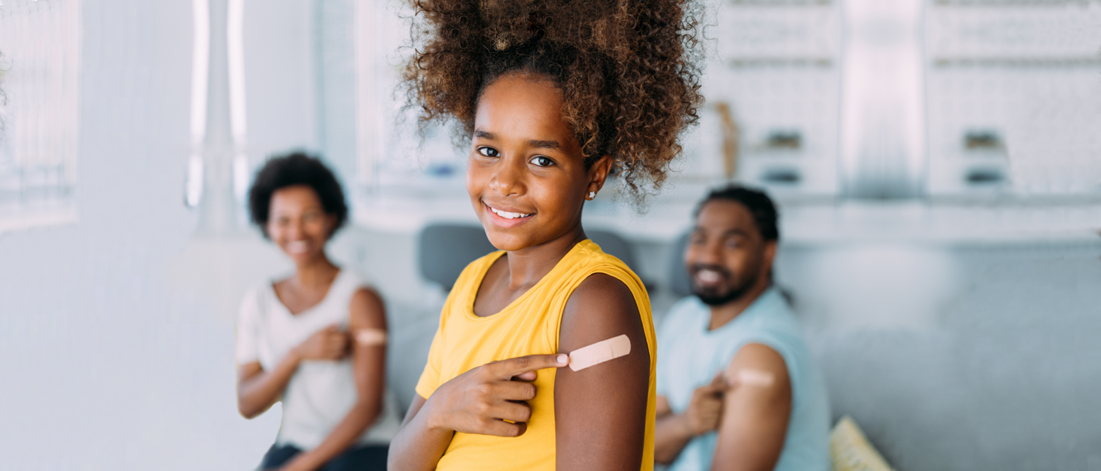 Little girl pointing at bandage on arm.