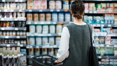 Mujer enfrete de anaquel de latas de comida