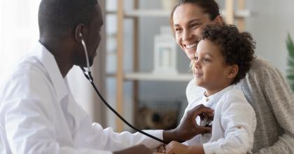 African American Pediatrician Holding Stethoscope Up to a Child