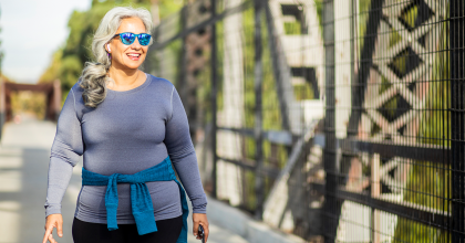Mexican woman wearing blue sunglasses walking on a sunny day.