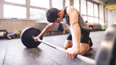 Adolescente agarrando una barra en el piso del gimnasio.