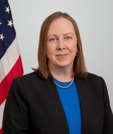 Heidi Rebello headshot with flag in the background.