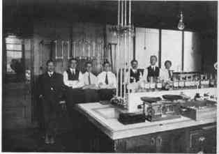 7 men behind a lab table.