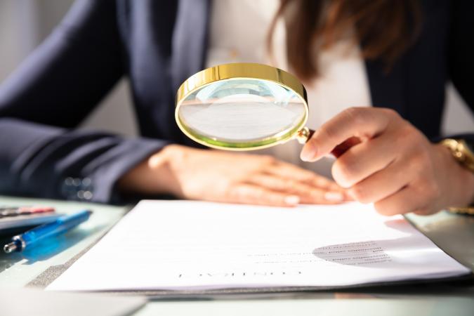 Person holding a magnifying glass over a piece of paper