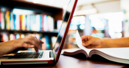 laptop and open book in a library