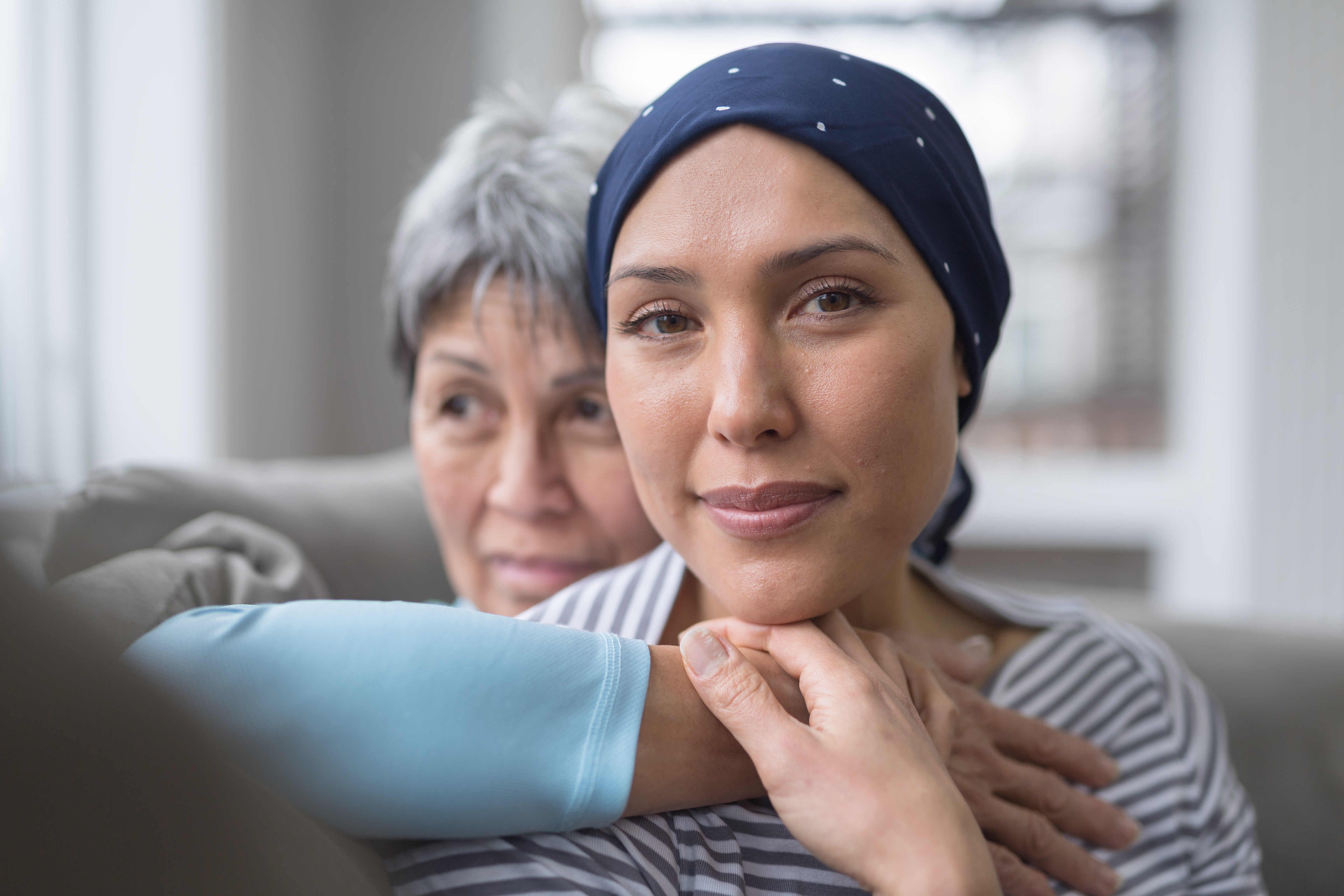 Image of older Asian woman embracing younger woman battling cancer