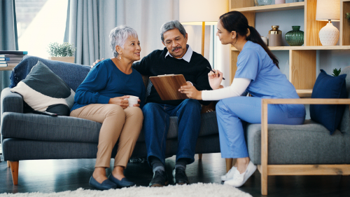 Older couple being assisted by nurse holding a clipboard