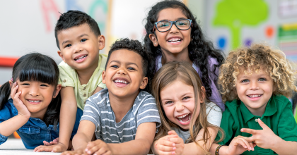 Photo of diverse group of small children smiling in a classroom