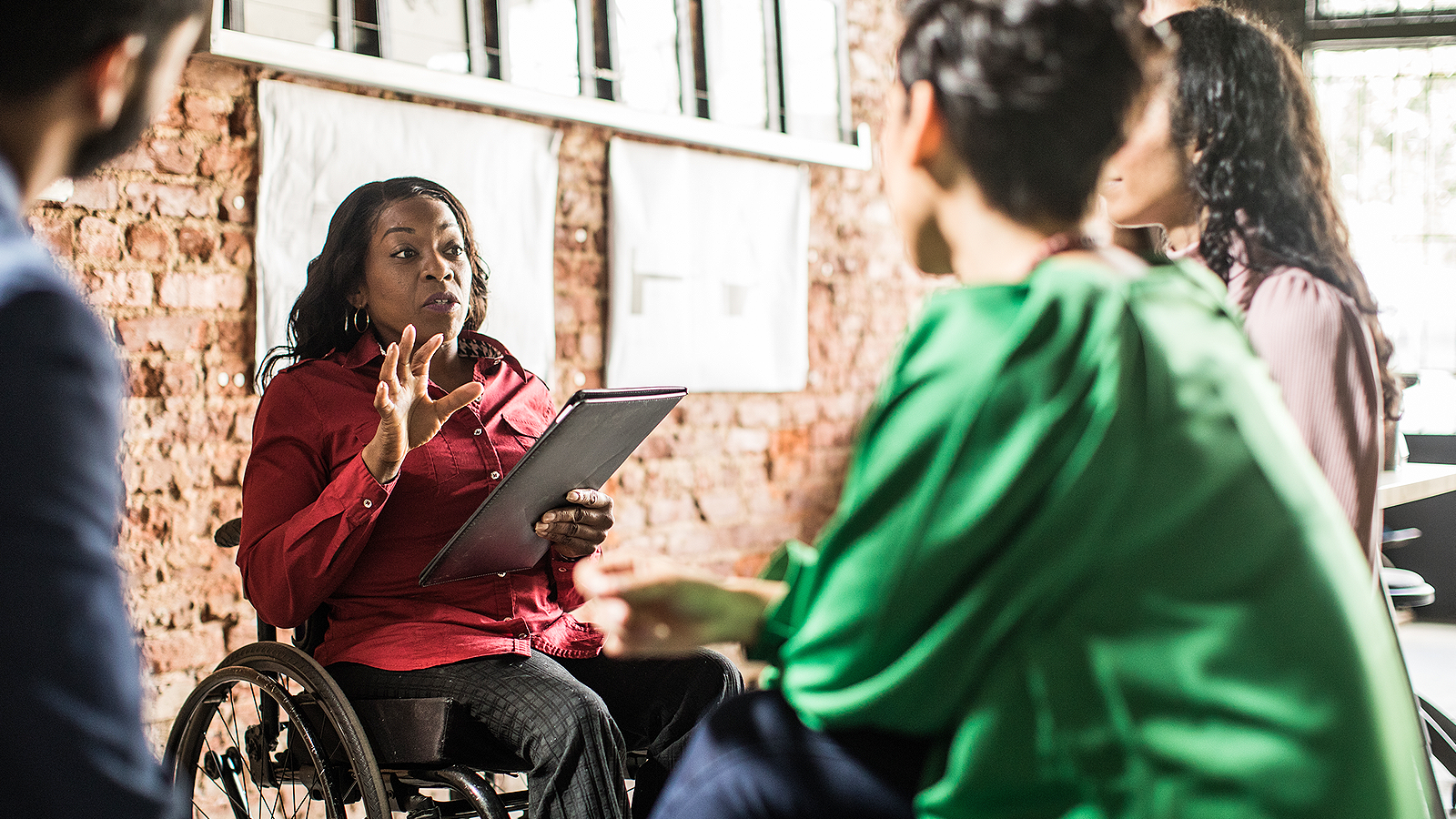 Woman in wheelchair leading a group discussion in an office.