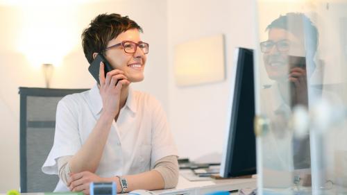 Female scientist holding a cell phone to her ear and smiling. Scientific Evidence for Cell Phone Safety.