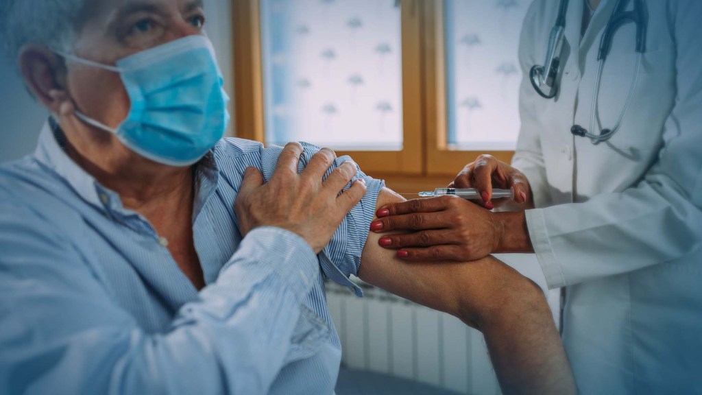 An elderly man getting a vaccine by a doctor