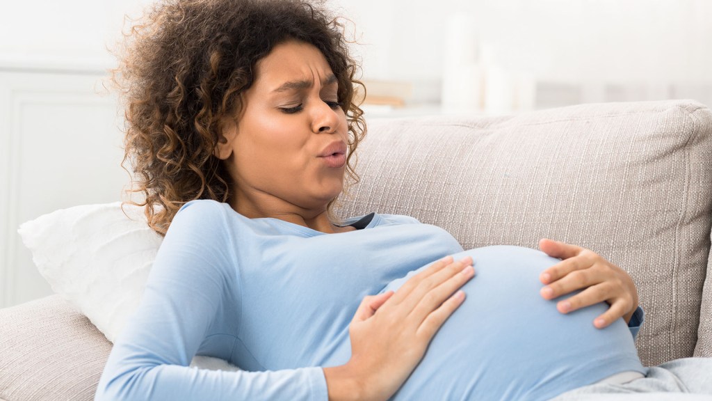 A pregnant woman is on a couch and in labor
