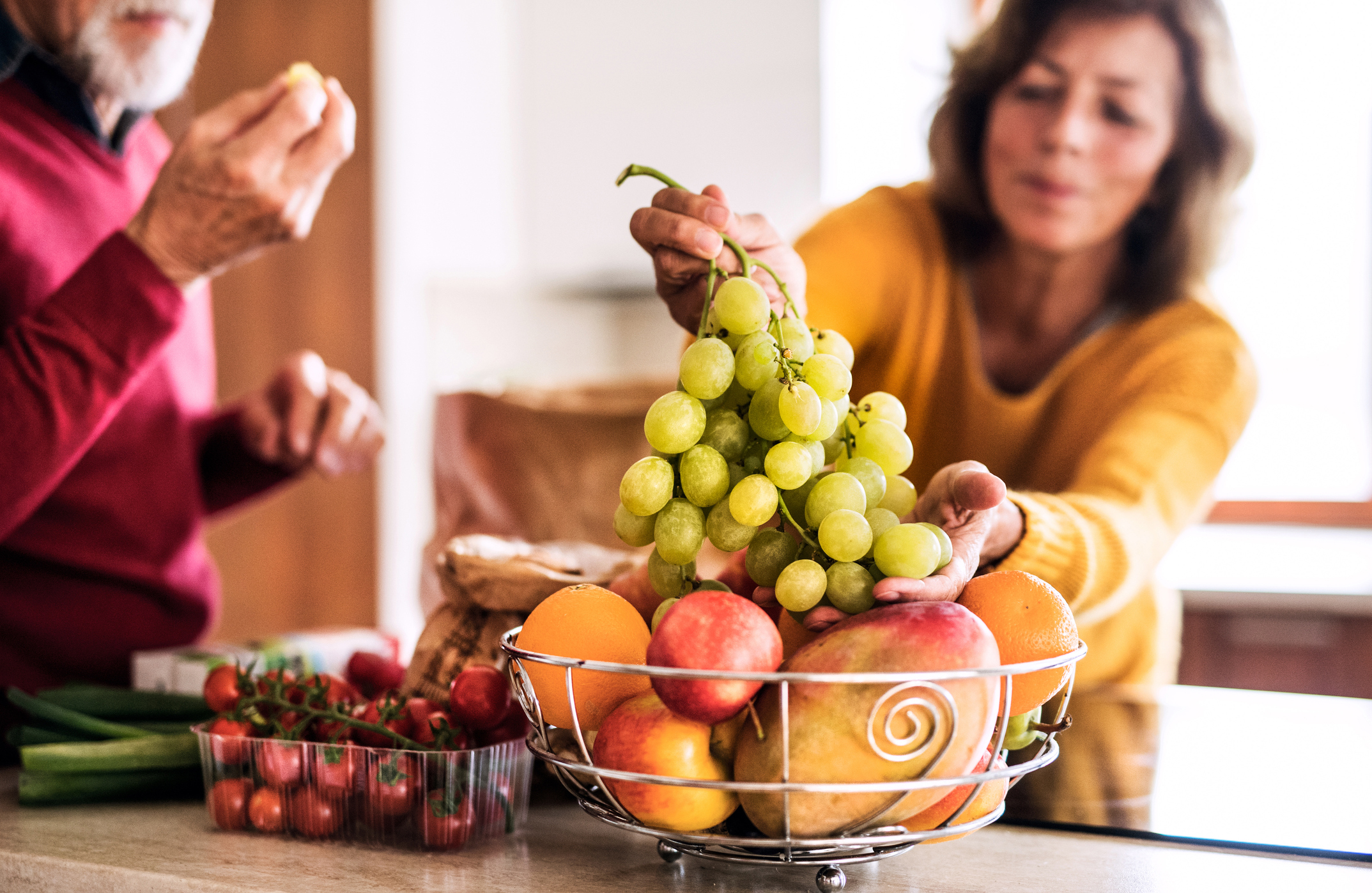 Woman choosing grapes from a basket of fruit