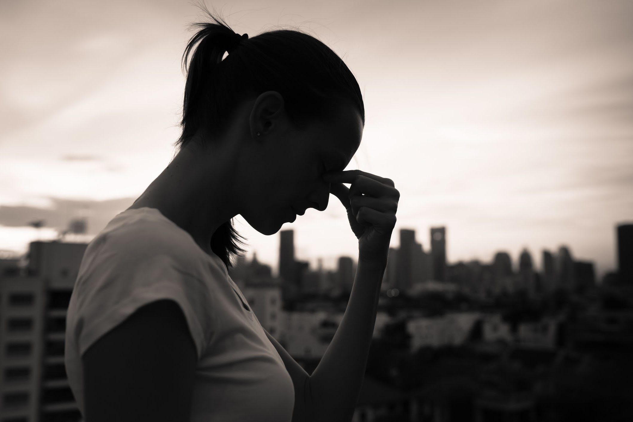 Silhouette of a woman resting her head in her hands